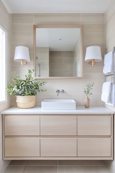 a bathroom with a sink, mirror and plants on the counter top in front of it