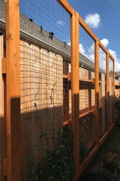 the fence is made of wood and has metal bars on each side, along with plants