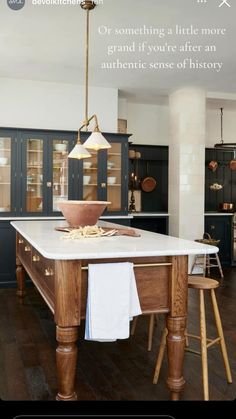 a large kitchen with wooden floors and dark blue cabinetry, along with white counter tops