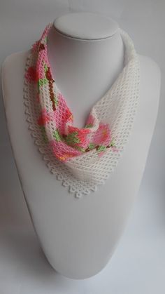 a white mannequin with a pink and green scarf on it's neck