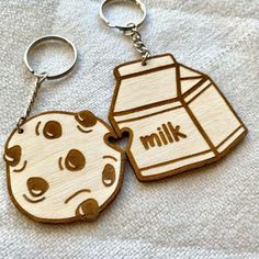 two wooden key chains with an image of a cookie and milk carton on them