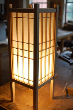 a lamp that is on top of a wooden table in a room with lots of windows