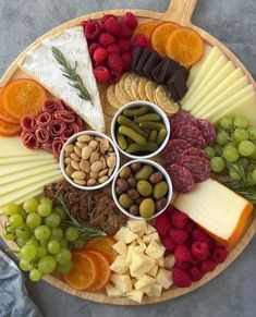 a platter filled with cheese, crackers, fruit and nuts