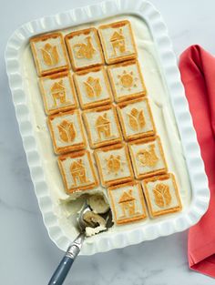 a pan filled with food on top of a white counter next to a red napkin