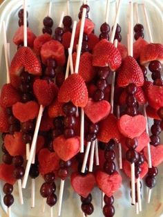 strawberries and cherries are arranged on skewers in the shape of hearts