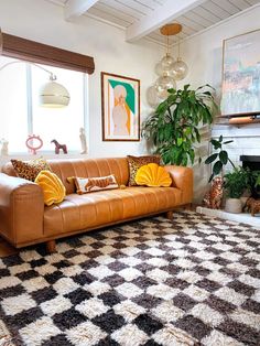 a living room with a couch, rug and potted plants in the window sill