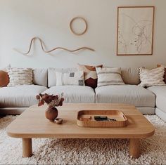 a living room with a white couch and wooden coffee table in front of a painting on the wall