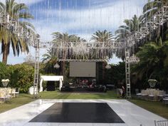 an outdoor event setup with white drapes and palm trees