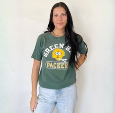 "70's Green Bay Packers t-shirt in good vintage condition. Perfectly distressed. Size tag marked size M but would fit modern day women's size small best. Please refer to all photos for wear. Length: 23\", shoulder to hem Width: 17\", pit to pit (Measured flat) A note on vintage t-shirt sizing: To ensure a perfect fit, we recommend measuring your favorite t-shirt and comparing it to the measurements specified above for this item. PLEASE READ BEFORE PURCHASE: All of our items are pre-loved vintage and may show signs of wear. Please review all photos carefully and send any questions or requests prior to purchasing any item. ALL SALES ARE FINAL." 90s Green Tops With Letter Print, 90s Green Letter Print Tops, Green Sporty Top With Screen Print, Sporty Green Top With Screen Print, Green Sporty T-shirt For Game Day, Sporty Green T-shirt For Game Day, Green Tops With Letter Print For Game Day, Green Letter Print Tops For Game Day, Green Graphic Tee For Game Day