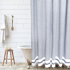 a bathroom with a bathtub, shower curtain and wooden stools in front of it