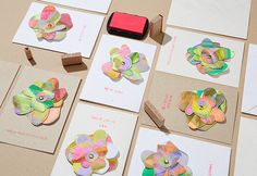 several different types of paper flowers are laid out on top of cards and envelopes