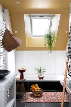 a bathroom with black and white tile flooring next to a bathtub under a skylight