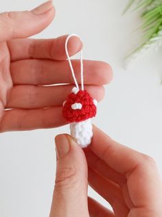 a hand holding a small crocheted santa hat ornament in white and red