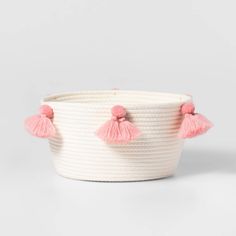 a white basket with pink tassels on it