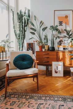 a living room filled with lots of plants next to a wooden dresser and chair on top of a hard wood floor