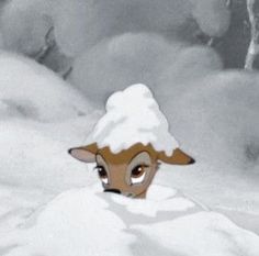 a deer is peeking out from the snow covered ground