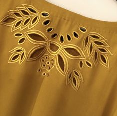 a close up view of a yellow dress with leaves and berries on it