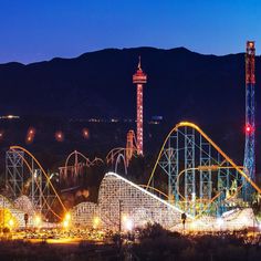 an amusement park at night with roller coasters lit up