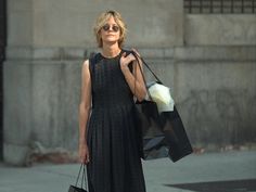 a woman in black dress carrying shopping bags