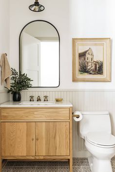 a white toilet sitting next to a wooden cabinet in a bathroom under a large mirror