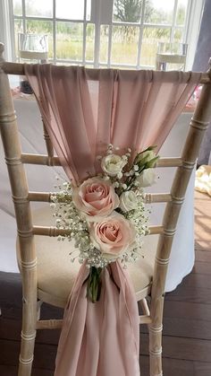 a chair decorated with pink sashes and white flowers on the back, along with baby's breath