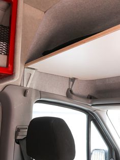 the interior of a vehicle with an open window and red shelf on the side wall