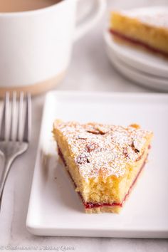 a piece of cake sitting on top of a white plate next to a cup of coffee