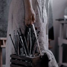 a person holding a wooden box filled with lots of different types of knives and tongs