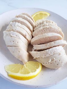 sliced chicken with lemon slices on a white plate