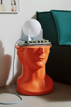 an orange mannequin head with a lamp on top of it