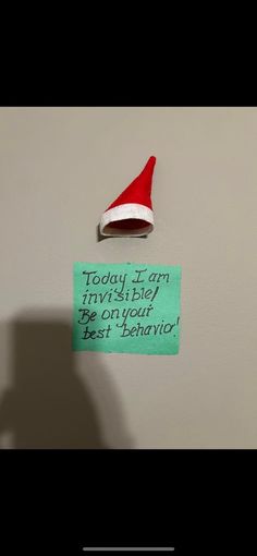 a santa hat is hanging on the wall next to a sign that reads, today i am