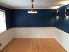 an empty room with blue walls and wood flooring in the center is lit by three lights