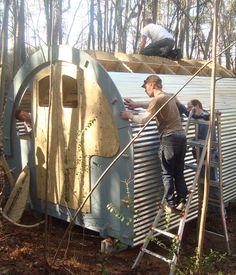 two men working on an old trailer in the woods