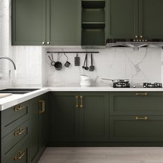 a kitchen with green cabinets and white counter tops, gold pulls on the cupboards