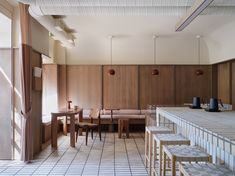 a kitchen with wooden walls and white tile flooring next to a counter top covered in stools