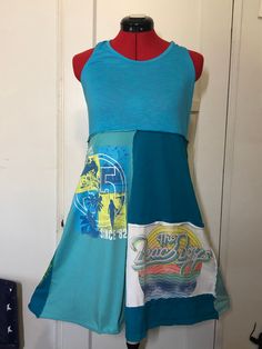 Blue Summer Upcycled Dress, Beach Boys and beach themed, made from gently used tee shirts. Racer back and empire waist. This dress is fun and comfy and perfect for a day at the beach. Approximately a women's size 10. Empire waist is 18 inches across and shoulder to hem is 35 inches. Blue Summer Dress, Upcycled Dress, Altered Clothing, Blue Summer Dresses, Beach Boys, Tee Shirt Dress, Dress Beach, Recycle Clothes, Patchwork Dress