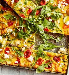 an overhead view of a pizza with tomatoes, cheese and arugula on it