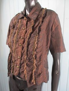 Very pretty chocolate brown ruffled blouse with short sleeves and a lace front. It has a collar and small silver buttons down the front. Dimensions: Bust: 40 Inches. Length: 21 Inches. Made in France Elegant Brown Tops With Collar, Brown Ruffled Top With Short Sleeves, Brown Short Sleeve Tops With Buttons, Spring Collared Brown Blouse, Brown Collared Spring Blouse, Collared Brown Blouse For Spring, Fitted Collared Shirt With Ruffles, Fitted Short Sleeve Fall Blouse, Fitted Collared Brown Shirt