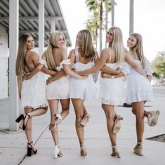 four beautiful young women walking down the street in white dresses and high heeled sandals