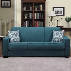 a blue couch sitting in front of a book shelf