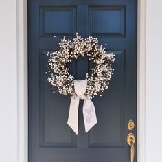 a blue door with a wreath on it and a white ribbon hanging from the front