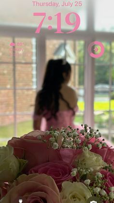 a woman standing in front of a window holding a bouquet of flowers