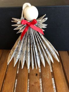 an ornament made out of old book pages with a red ribbon on it