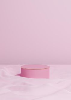 a pink box sitting on top of a white bed next to a light pink wall