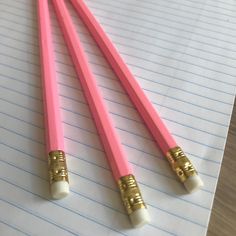 two pink and gold pencils on lined paper