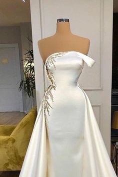 a white wedding dress on display in front of a mannequin headdress