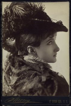 an old photo of a woman wearing a hat with feathers on it's head