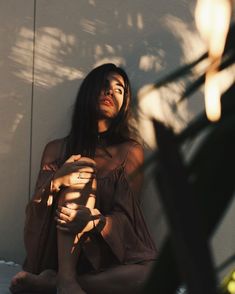 a woman sitting on the ground next to a plant