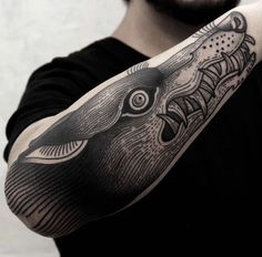 a man with a black and white tattoo on his arm holding up a large fish