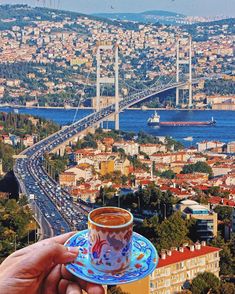 a cup of coffee on a saucer in front of a view of a bridge